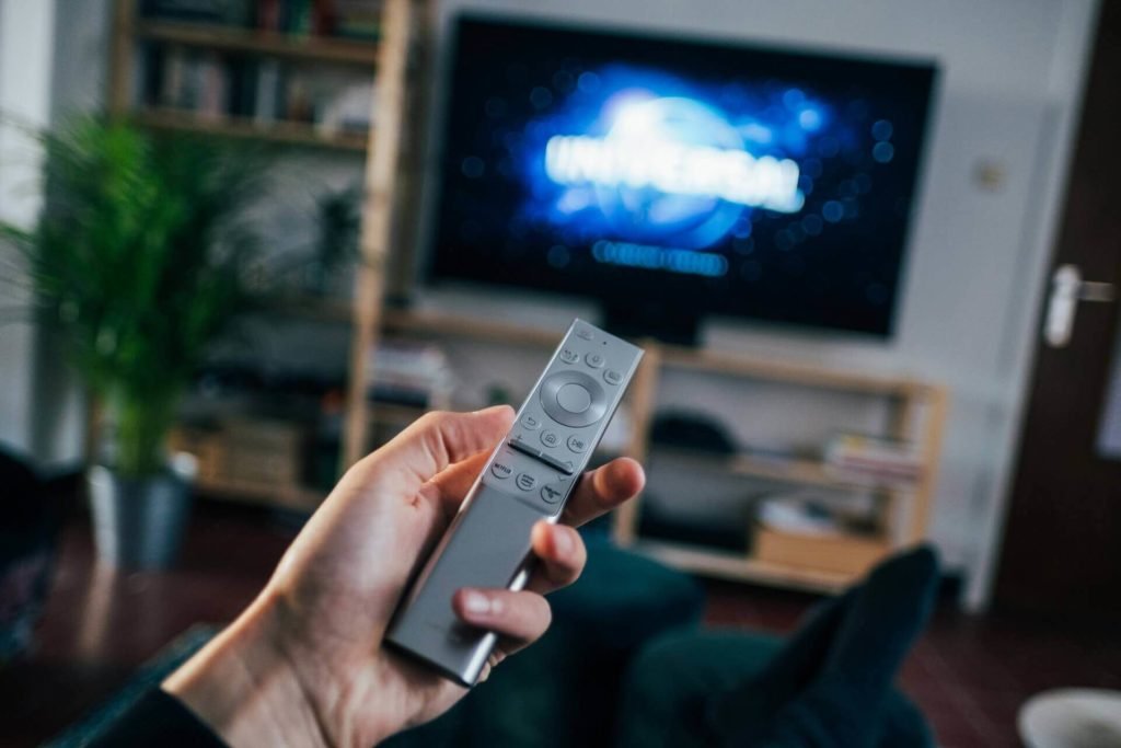 A tv remote and movie showing on the tv screen