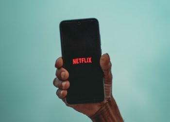 A man holding a phone with Netflix logo
