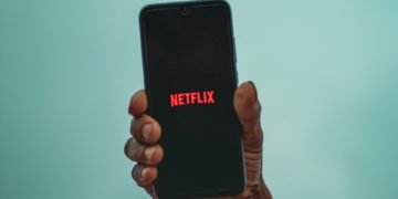 A man holding a phone with Netflix logo